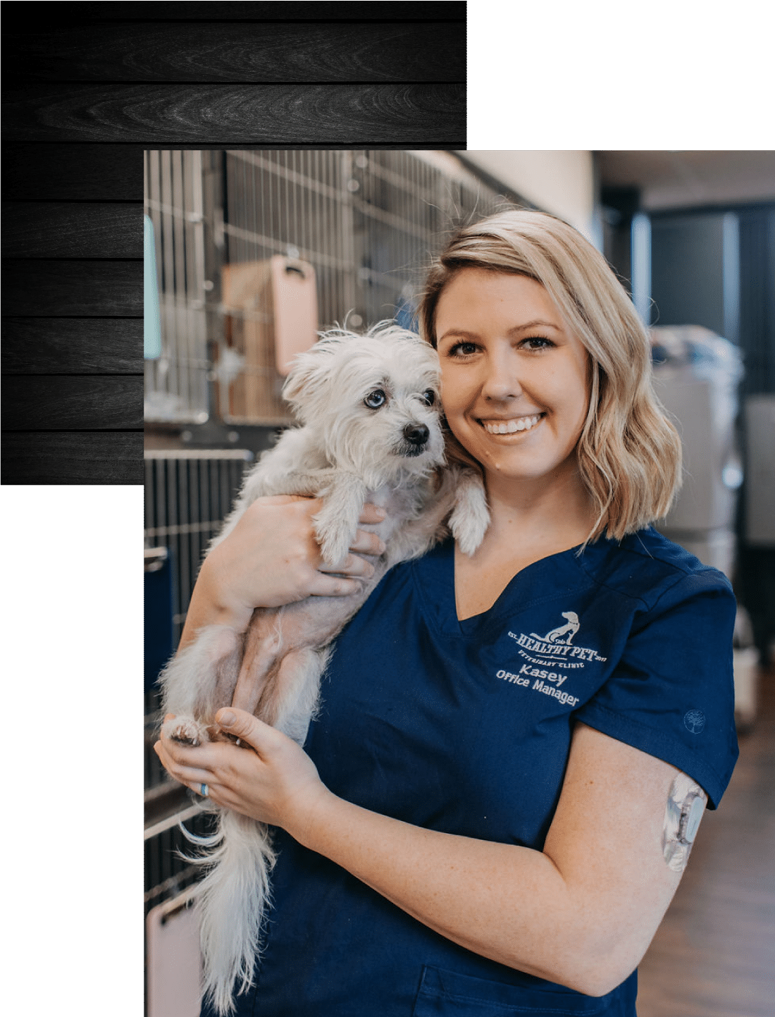 Kasey, the office manager, holding a small white dog while smiling at the camera